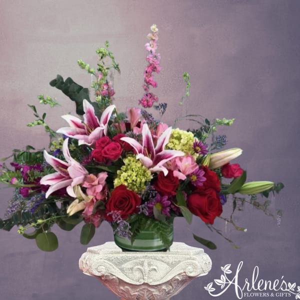 Pink lilies and red roses in a green glass vase