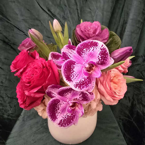 Pink roses and spotted orchids arranged in a white vase