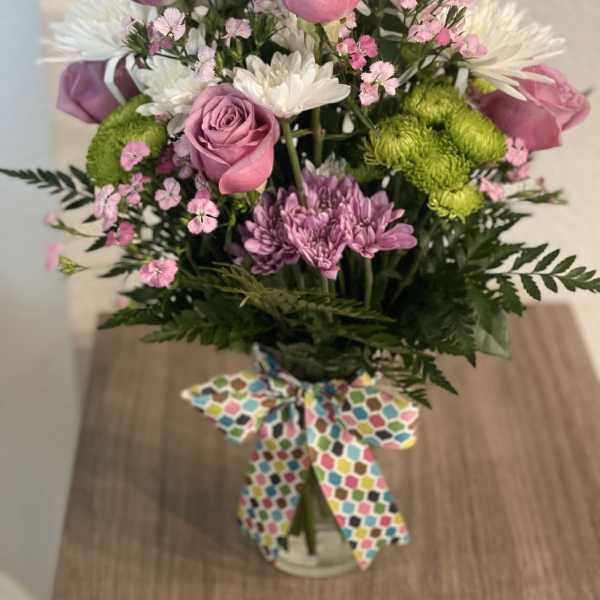 Bouquet of pink roses, white daisies, and green mums in a glass vase