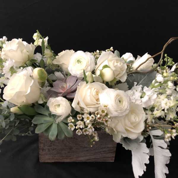 Cream floral arrangement in a wooden box with succulents and trailing greenery