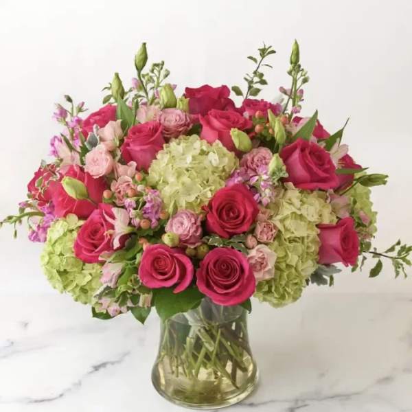 Pink roses and pale green hydrangeas in a clear glass vase
