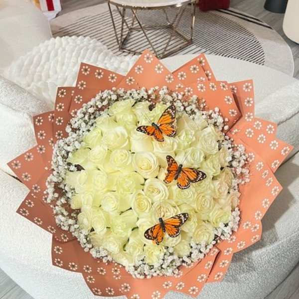 Bouquet of pale yellow roses with butterfly accents and peach wrapping