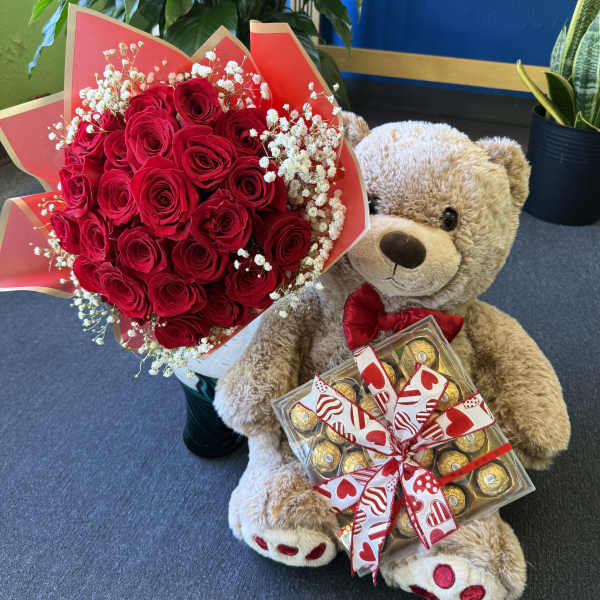 Red rose bouquet with baby’s breath beside a teddy bear holding chocolates