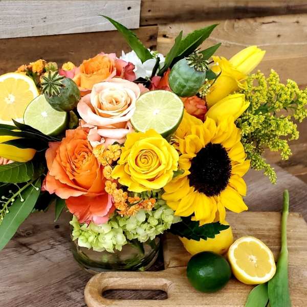 Bouquet of roses and sunflowers with citrus slices in a glass vase