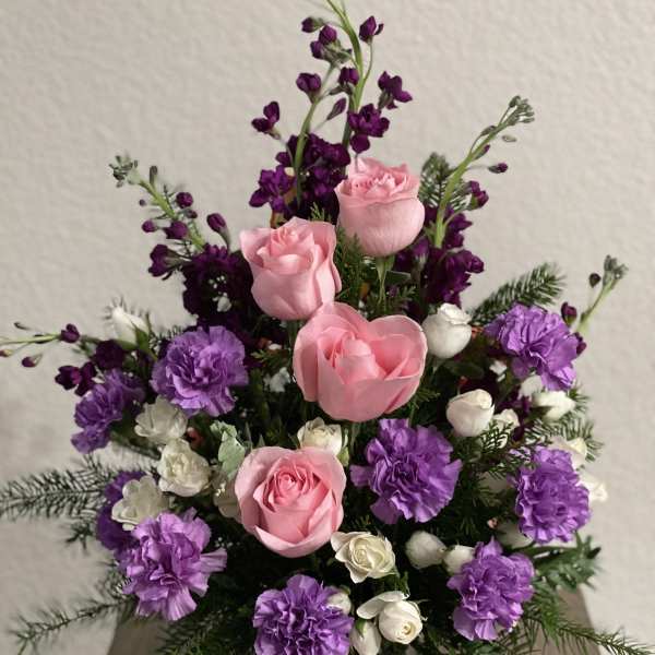 Pink roses and purple carnations in a green vase