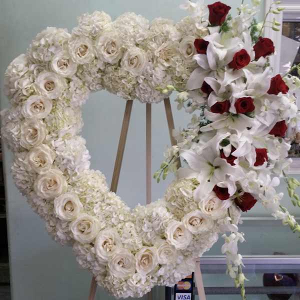 Heart-shaped floral wreath with white roses and red roses on an easel
