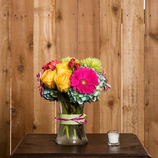 Colorful bouquet of roses, gerbera daisies, and hydrangeas in a glass vase