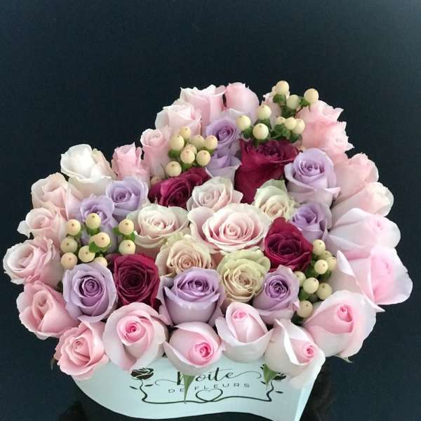 Bouquet of pastel roses and berry sprigs in a white box