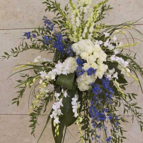 Tall white and blue floral standing spray on a black easel