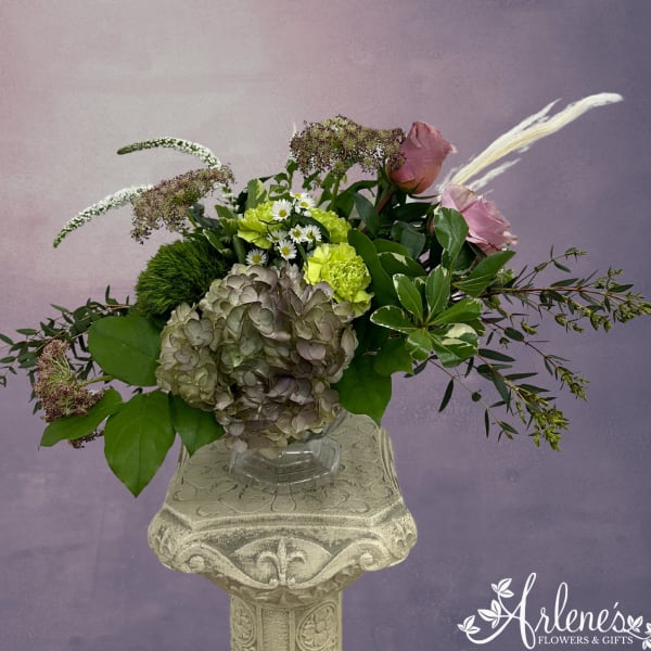 Mixed bouquet with pink roses, green hydrangea, and white filler flowers in a glass vase