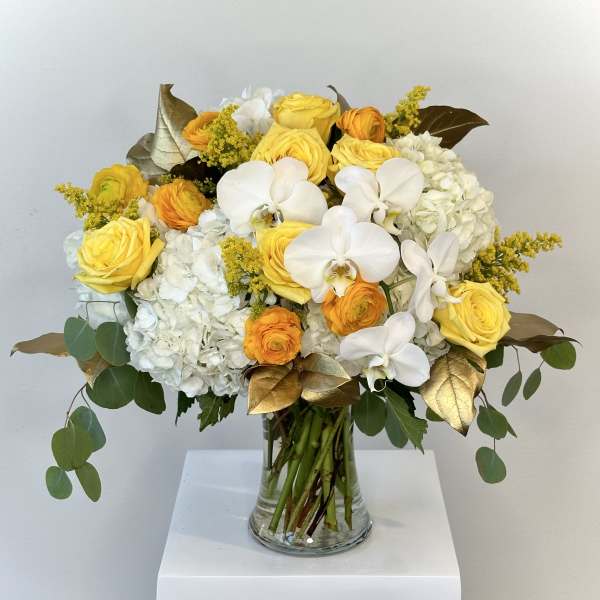 Yellow roses and white orchids in a glass vase