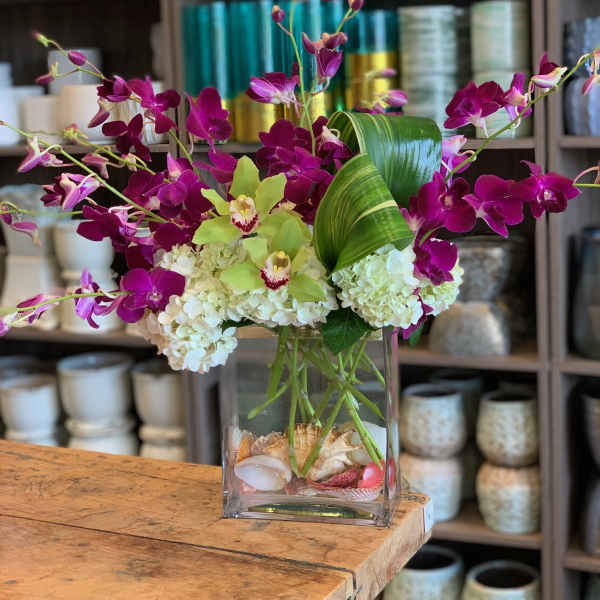 Purple orchids and white hydrangeas in a clear glass vase