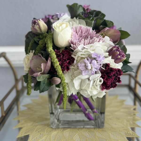 Mixed bouquet in a clear square vase with white, pink, and purple blooms