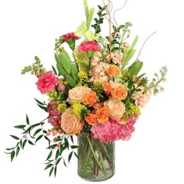 Mixed bouquet of peach, pink, and orange flowers in a glass vase