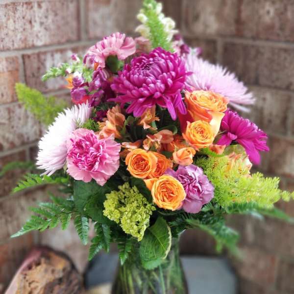 Mixed bouquet of pink, purple, and orange flowers in a glass vase