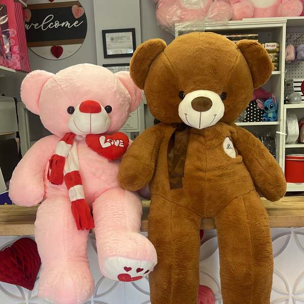 Two large teddy bears, one pink and one brown, displayed in a shop