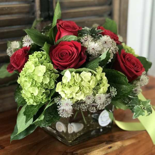 Red roses and green hydrangeas in a square glass vase