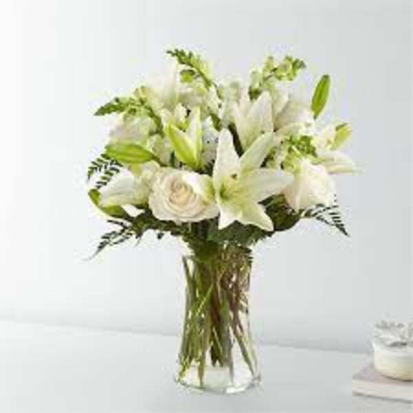 White lilies and roses arranged in a clear glass vase