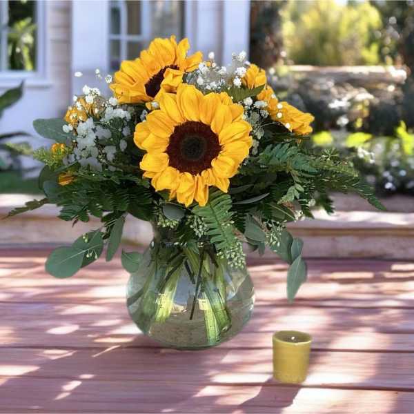 Sunflower bouquet in a glass vase with a small candle nearby