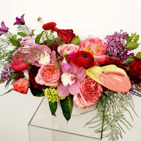 Mixed bouquet of pink, red, and purple flowers in a clear vase