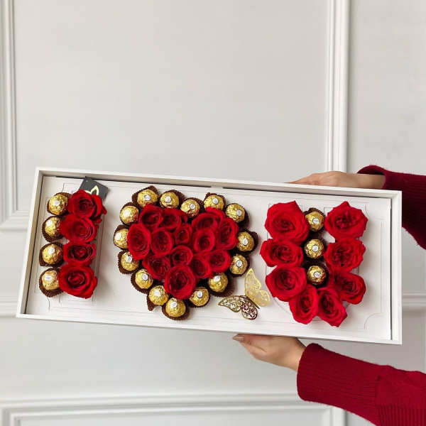 Red roses and gold chocolates arranged in a white gift box