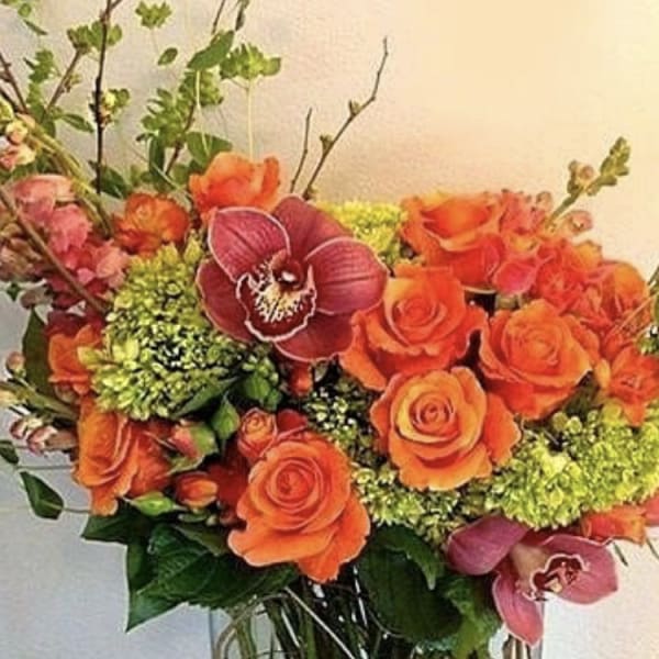 Bouquet of orange roses with pink orchids and green accents