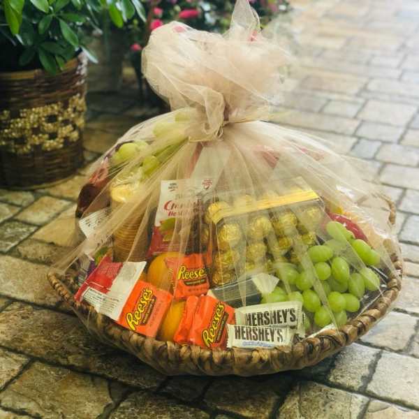 Gift basket with candy, fruit, and snacks wrapped in tulle