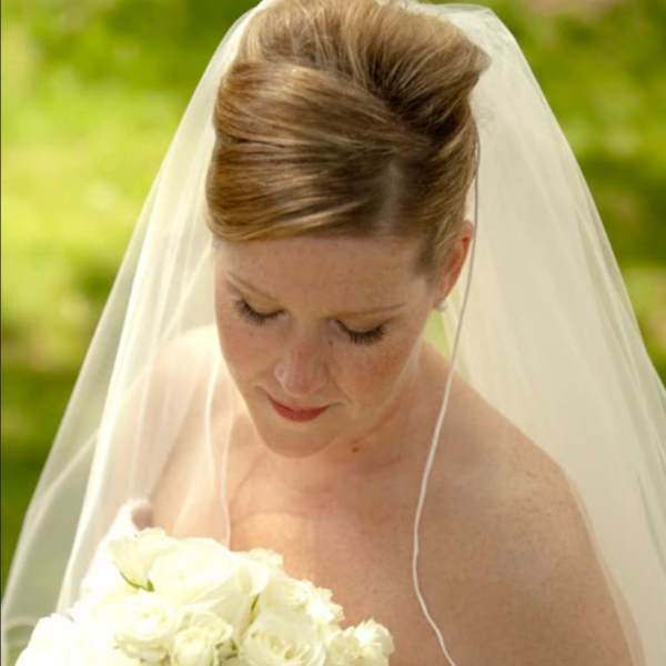 Bride holding a bouquet of white roses under a veil