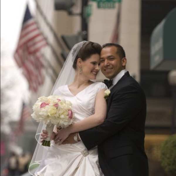 Bride and groom posing with a white and pink bouquet