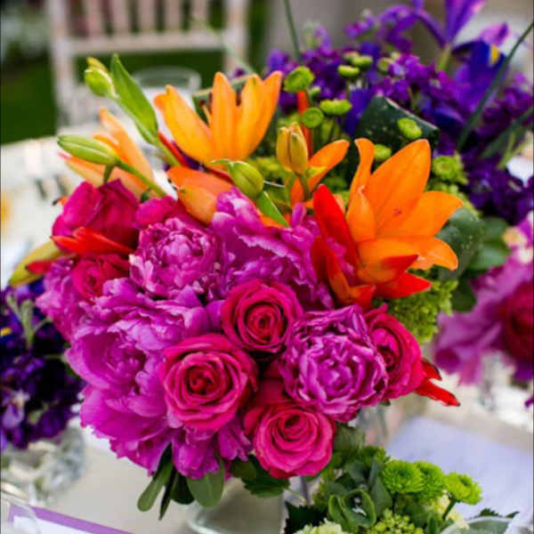 Bright mixed bouquet with pink roses, orange lilies, and purple flowers in a vase