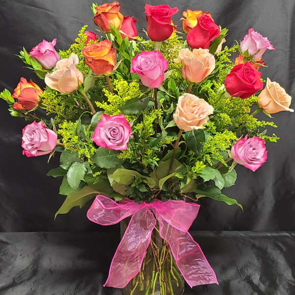 Bouquet of multicolored roses in a glass vase with a pink ribbon