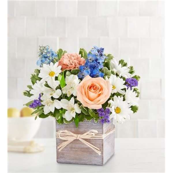 Mixed bouquet in a wooden box with daisies, roses, and blue flowers