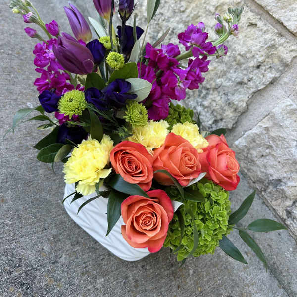 Colorful bouquet with roses, tulips, and purple blooms in a white vase