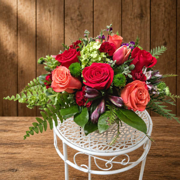 Mixed bouquet of red and coral roses in a white metal stand
