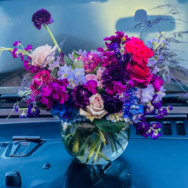 Bouquet of purple, pink, and blue flowers in a clear glass vase