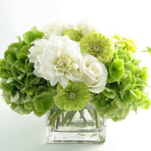 Green and white bouquet in a clear square vase