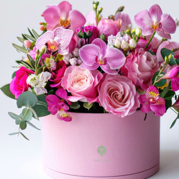 Pink roses and orchids arranged in a round pink box