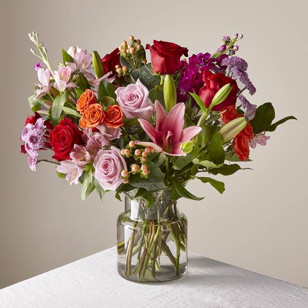 Mixed bouquet of roses, lilies, and alstroemeria in a glass vase