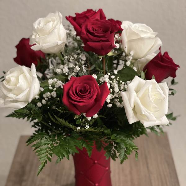 Red and white roses in a red vase with baby's breath
