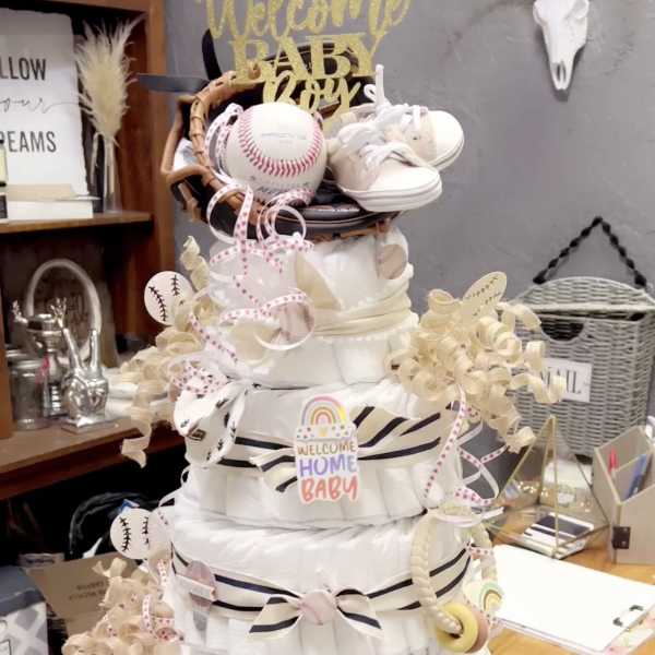 Diaper cake with baby shoes, baseballs, and ribbon decorations