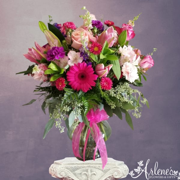 Mixed pink and purple bouquet in a glass vase with a ribbon