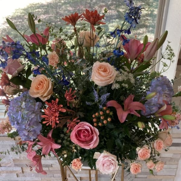 Large mixed floral arrangement with roses, lilies, hydrangeas, and blue flowers