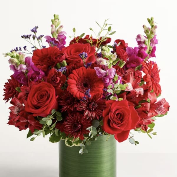 Red roses and mixed flowers in a green vase