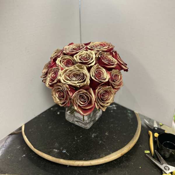 Bouquet of red and gold roses in a clear square vase