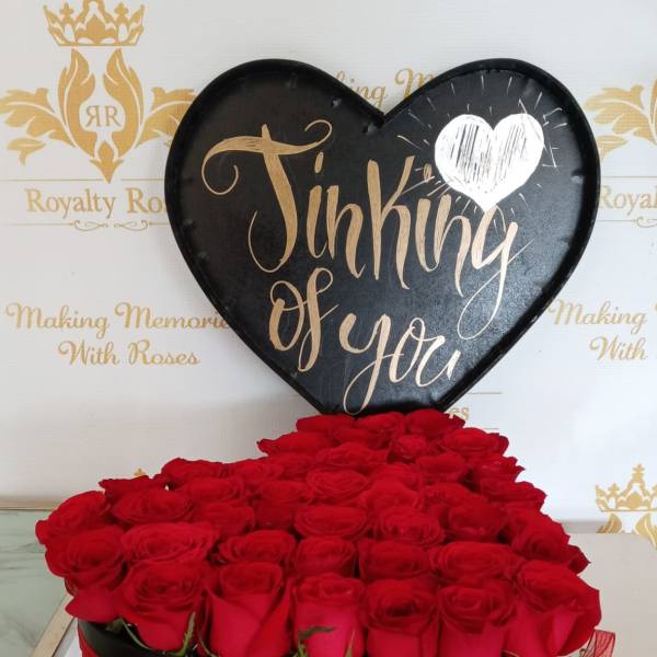Heart-shaped box of red roses with a black "Thinking of You" sign