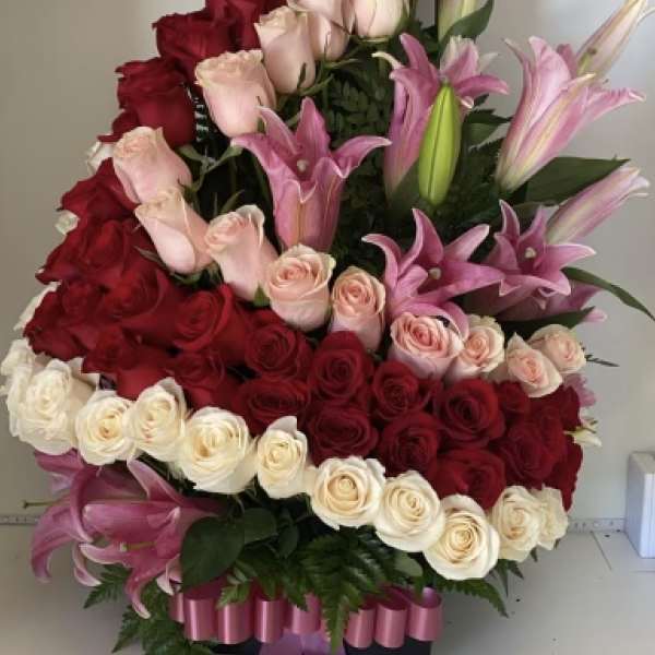 Large arrangement of red, pink, and white roses with pink lilies