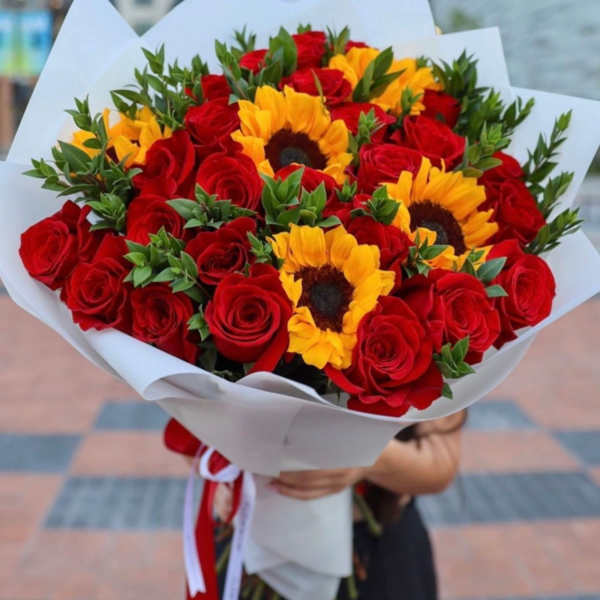 Bouquet of red roses and yellow sunflowers wrapped in white paper