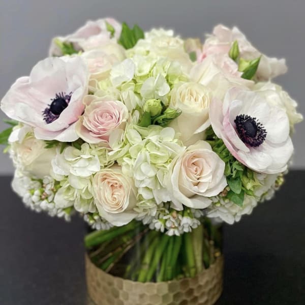 Wedding bouquet of white and blush flowers in a gold vase
