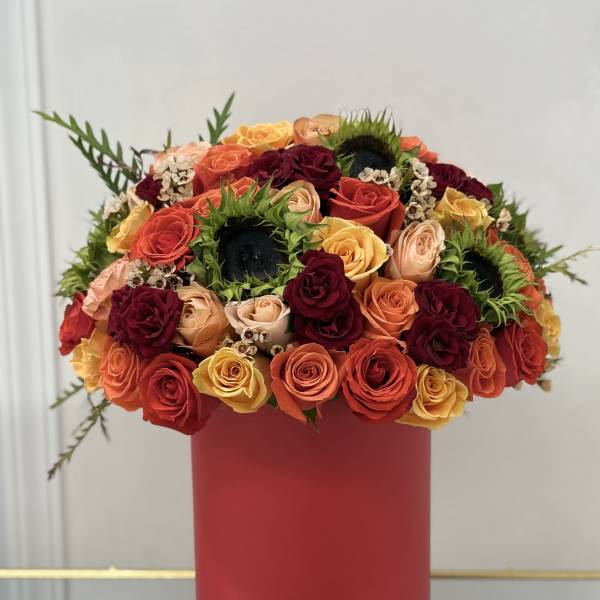 Round bouquet of multicolored roses in a red box