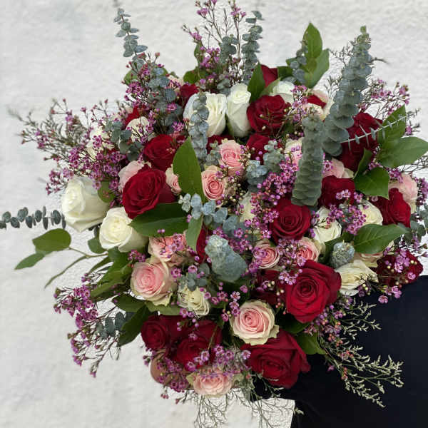 Bouquet of red, pink, and white roses with purple filler flowers